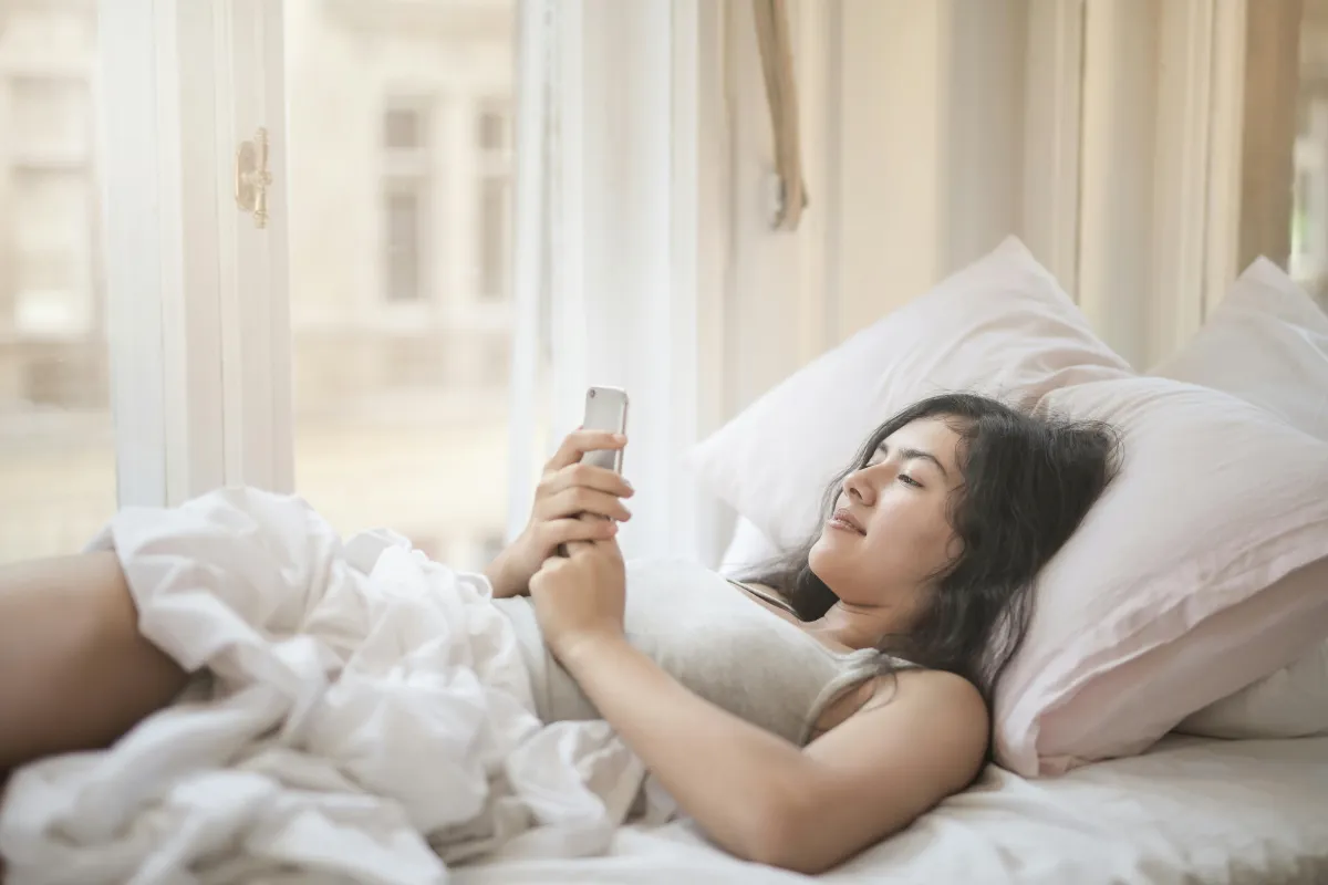 Person writing in a journal app on their phone in a cozy setting