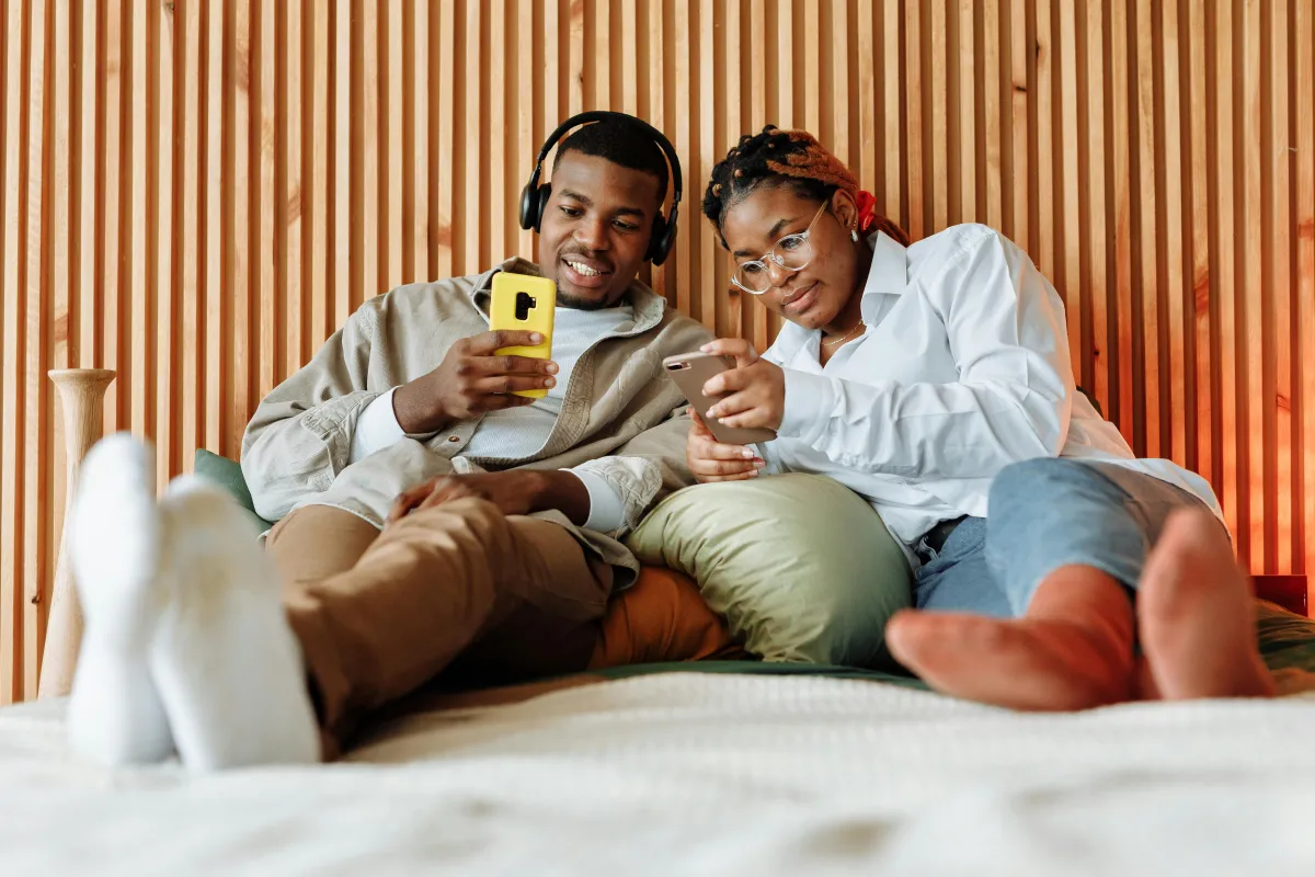 Couple using phones together with warm lighting at home