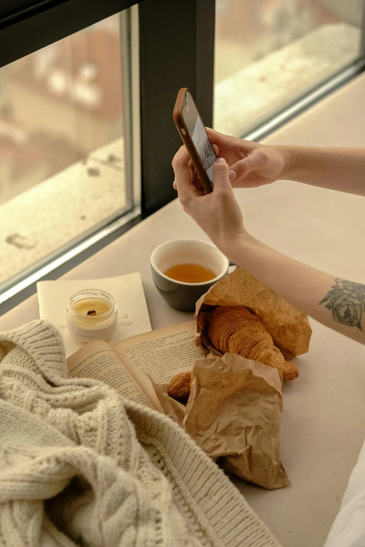 Person writing a short message on their phone while sitting by a window