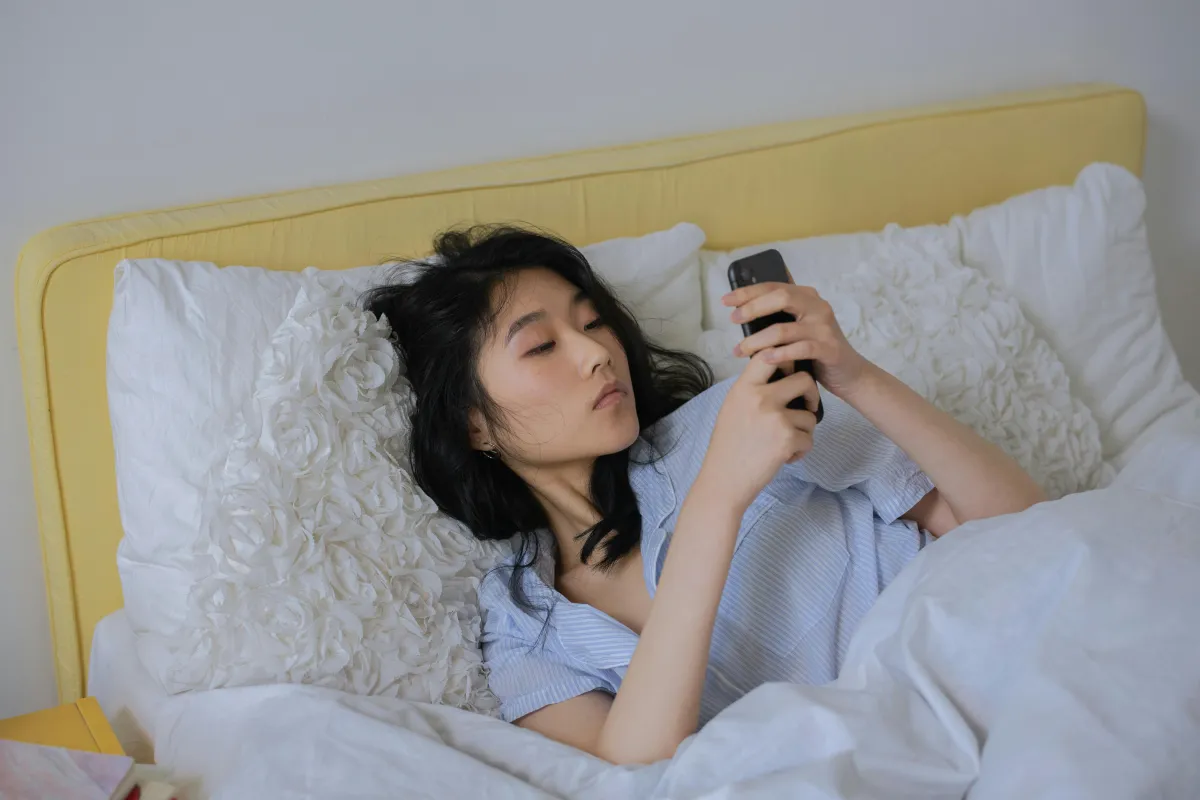 Person writing a message on their phone in a cozy room