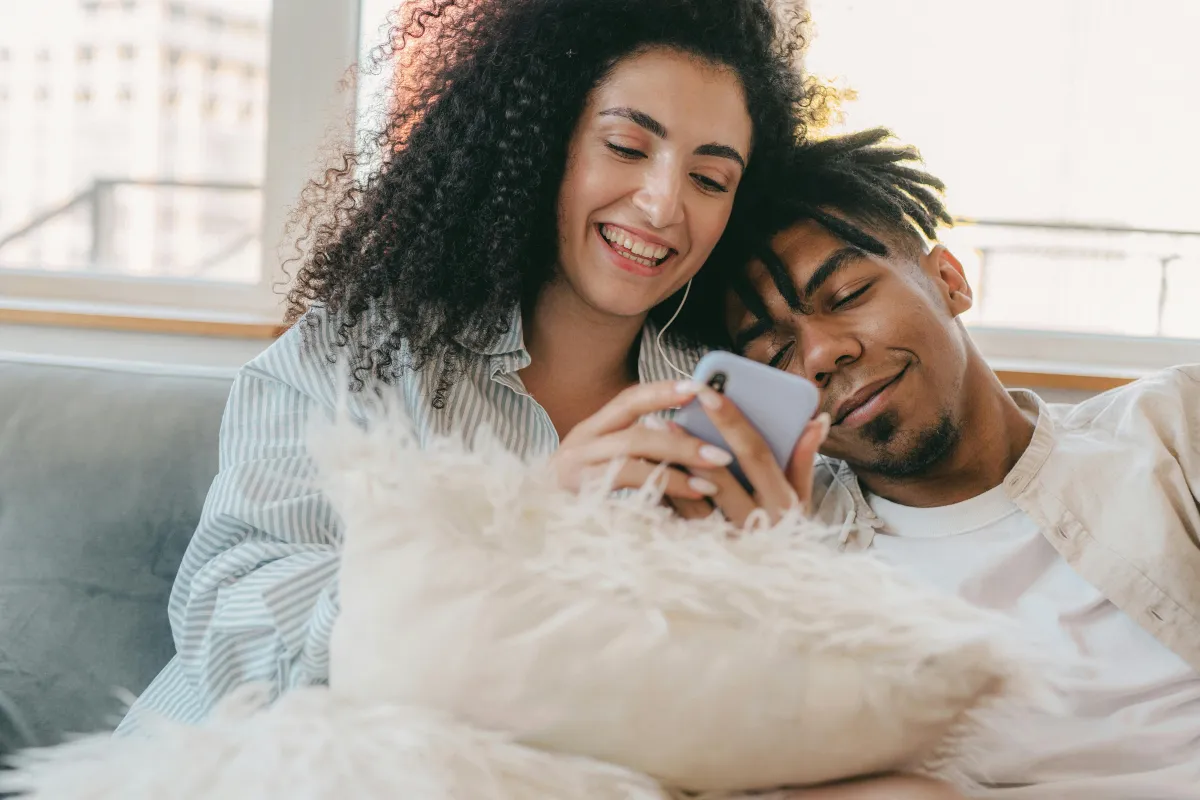 Couple looking at a phone together and smiling, small daily gestures relationship
